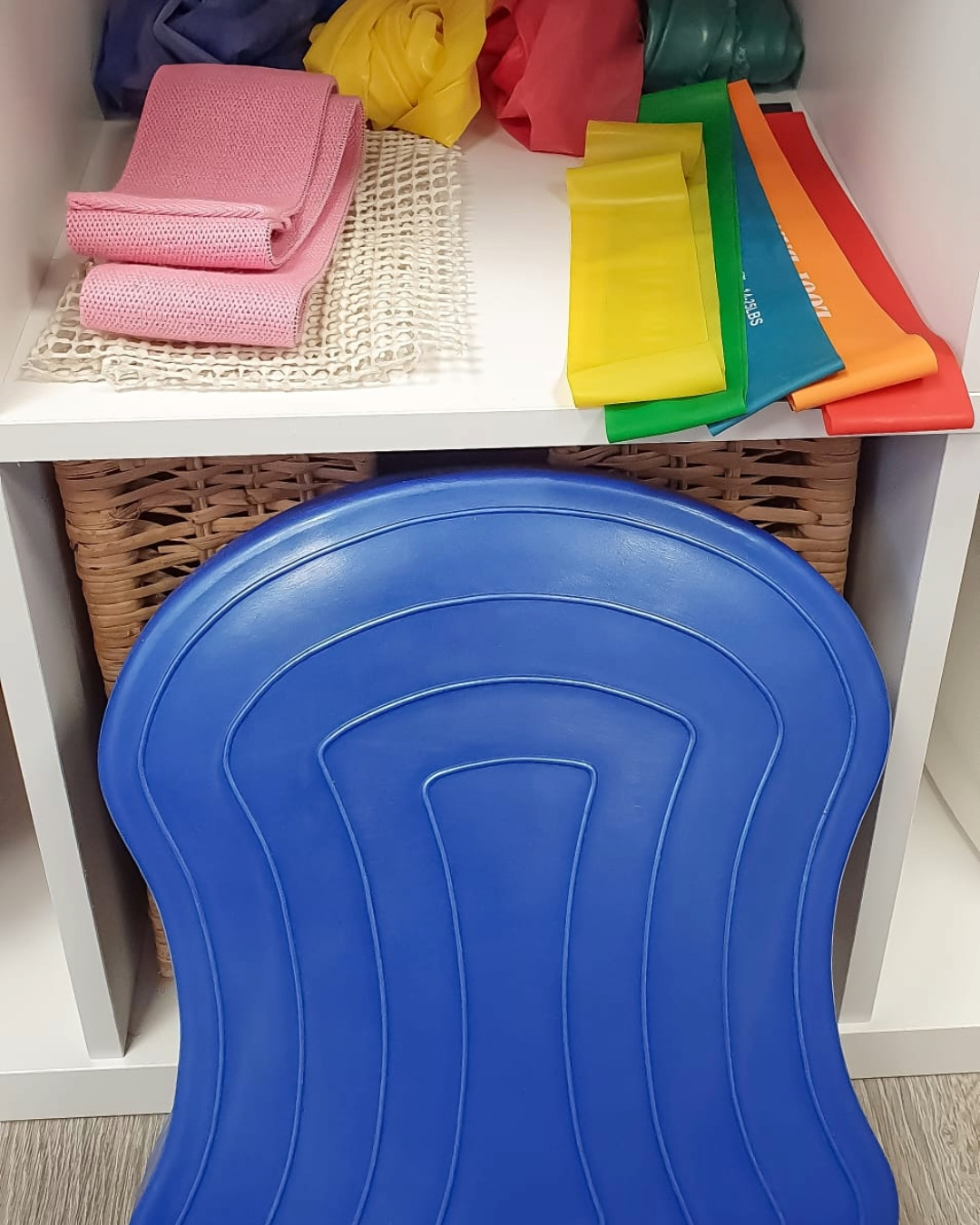 Foto di vari attrezzi per fisioterapia. In primo piano si trova una pedana per allenare l'equilibrio. In secondo piano si trovano vari elastici terapeutici.